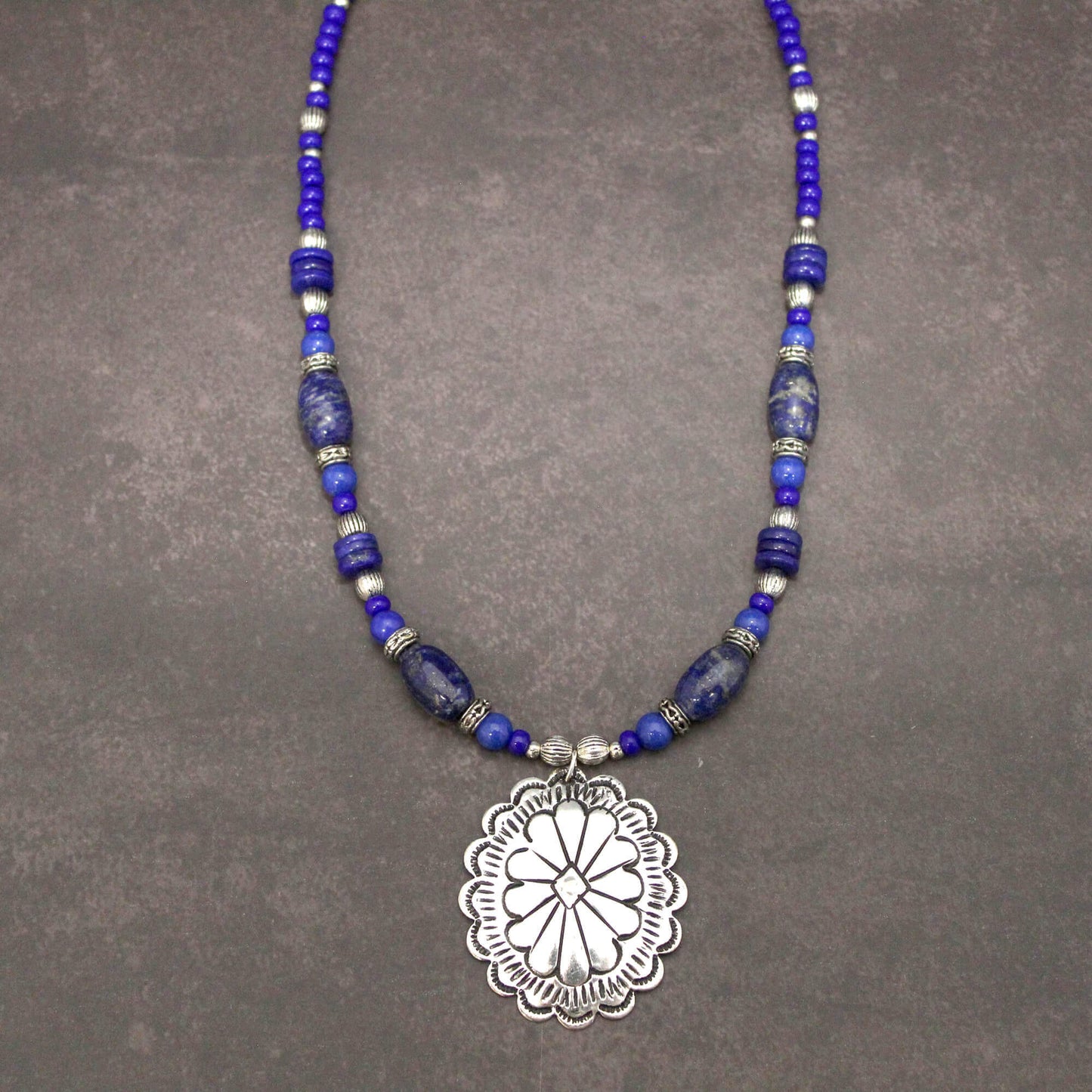 Perfect with Denim! A silver concho with Lapis Lazuli stones. The benefits consist of a powerful intense blue stone used to open minds and give enlightenment. This measures 18″ and an additional 1.75 pendant with an extender. Each piece is unique and may vary slightly.