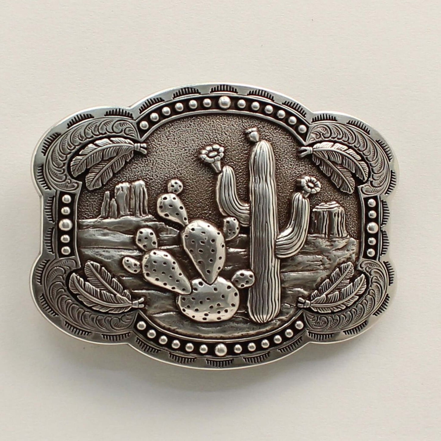 <span data-mce-fragment="1">This rectangle western buckle features a smooth edge with an antique desert scenery in the background with stamped cactus. There is western scrolling and feathers on the corners and small dots on the edges. </span><span data-mce-fragment="1" lang="EN-US">Measures: 3-3/4 x 3-1/4 Imported</span>