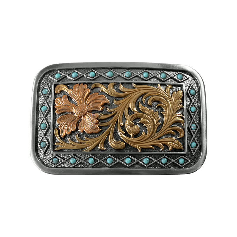 A western-style belt buckle featuring a rectangular silver-toned metal frame with turquoise stone accents and a central floral motif in gold and copper tones on a dark oxidized background.