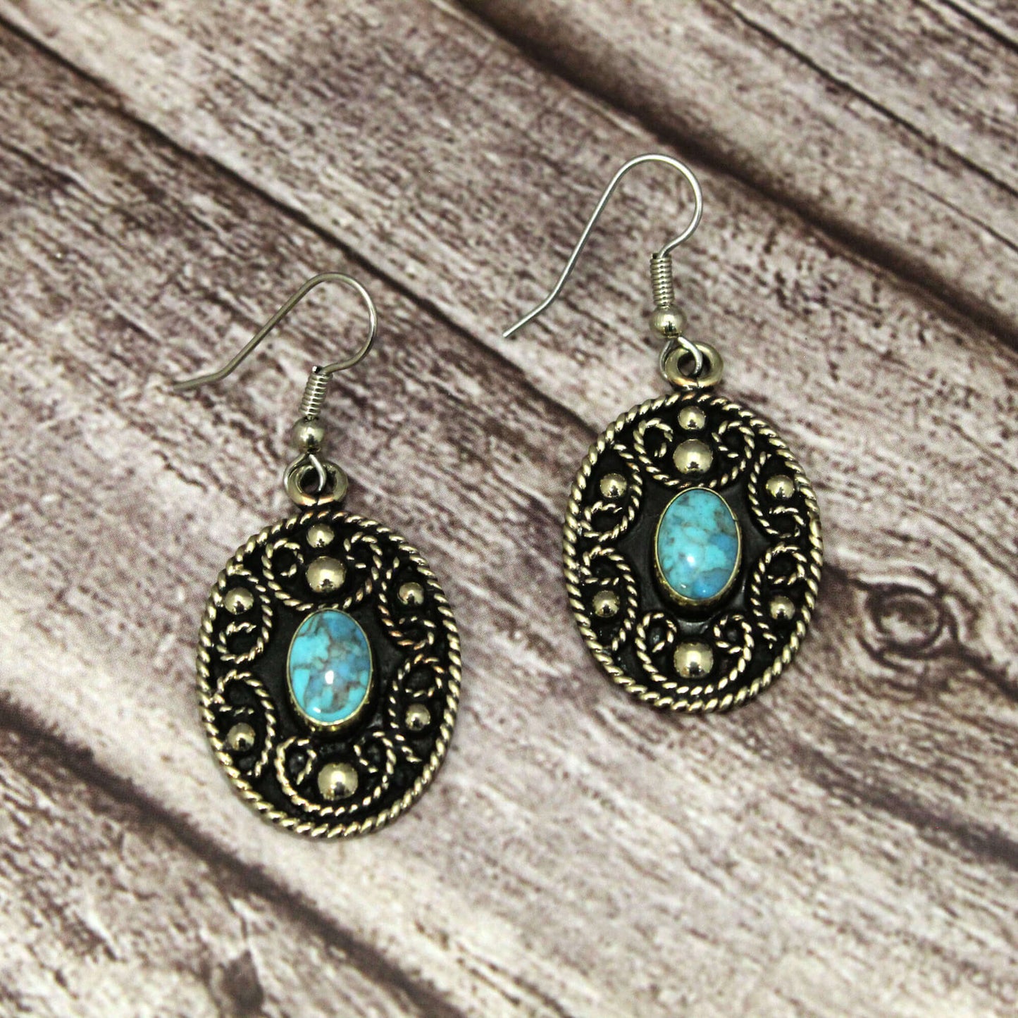Pair of earrings with turquoise stones on a wooden surface