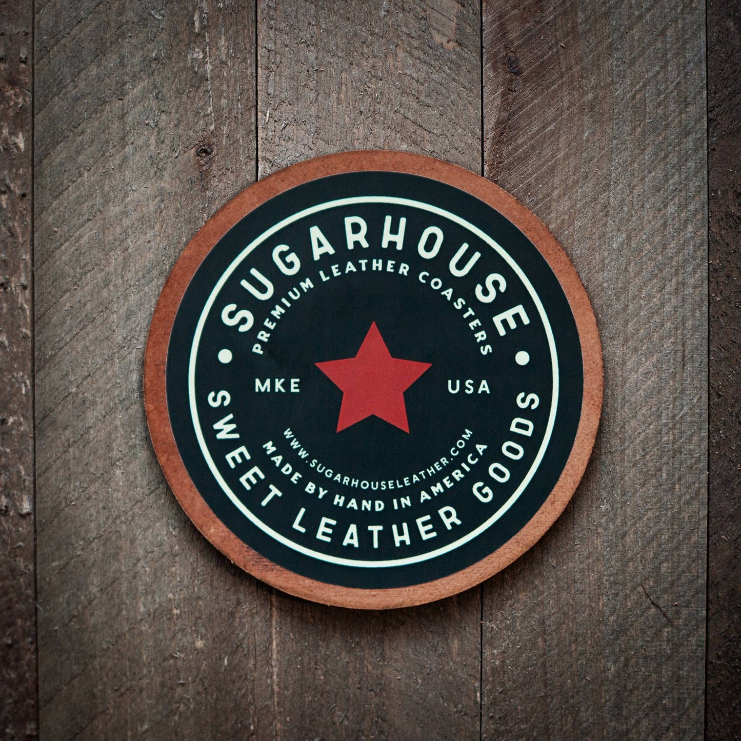 Round leather coaster with 'Sugarhouse Sweet Leather Goods' branding on a wooden surface