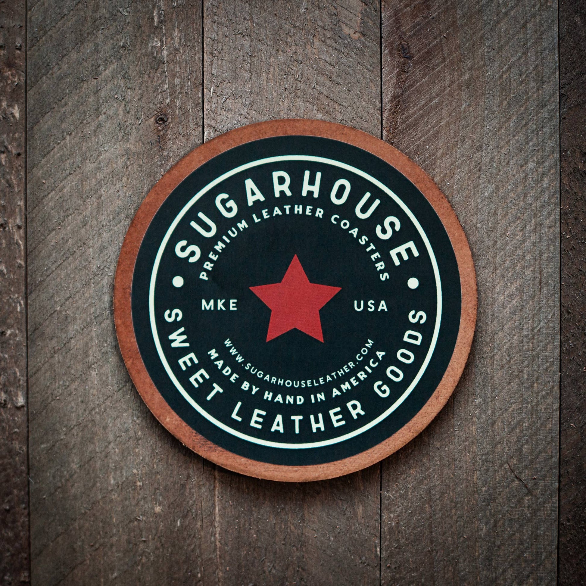 Round leather coaster with 'Sugarhouse Sweet Leather Goods' branding on a wooden surface