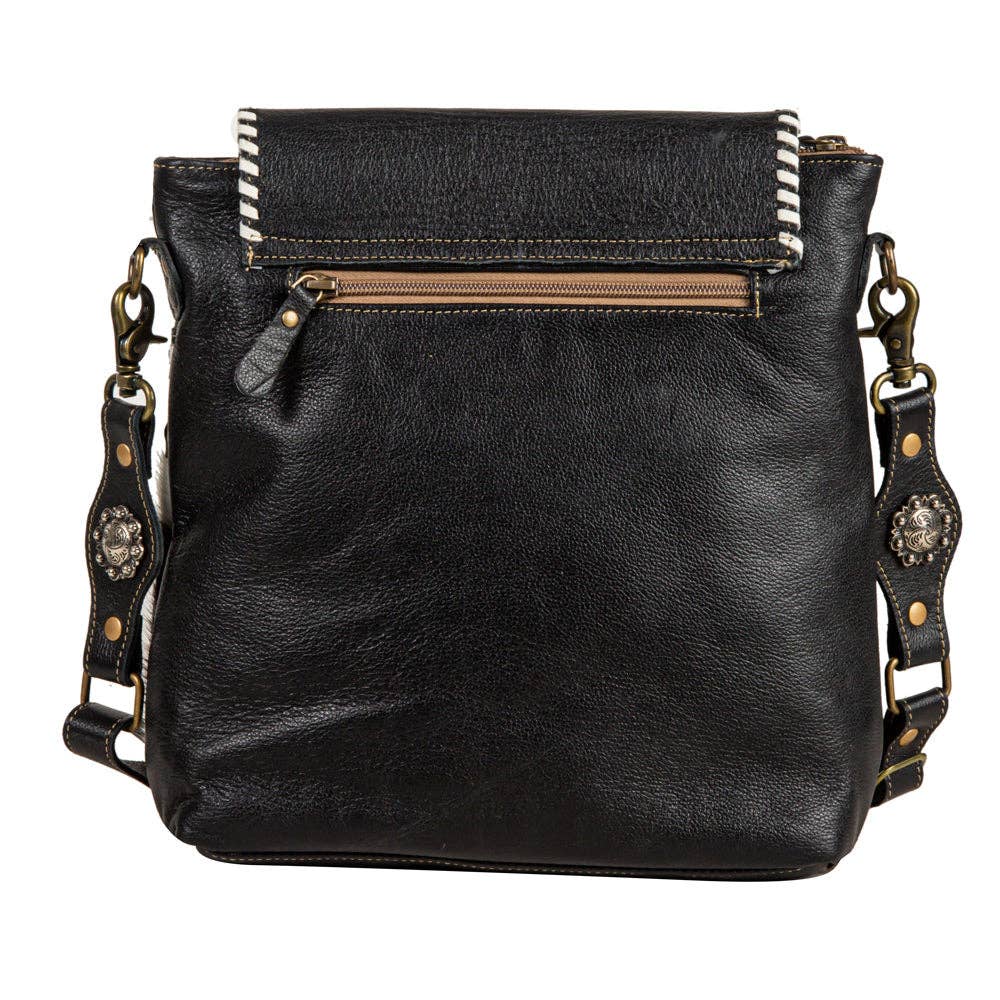 Black leather handbag with decorative straps on a white background
