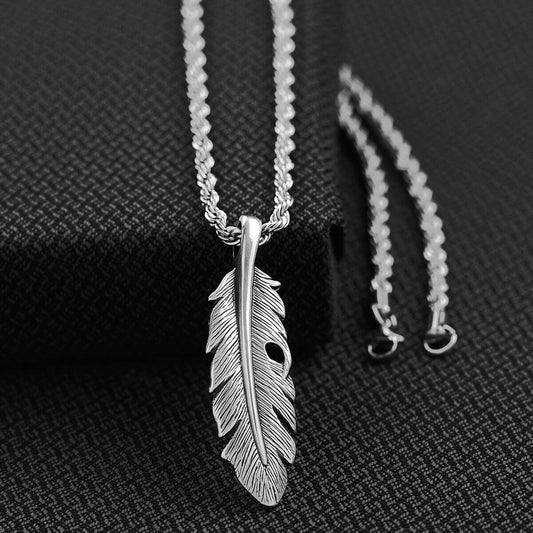 Silver feather pendant necklace on a textured black background