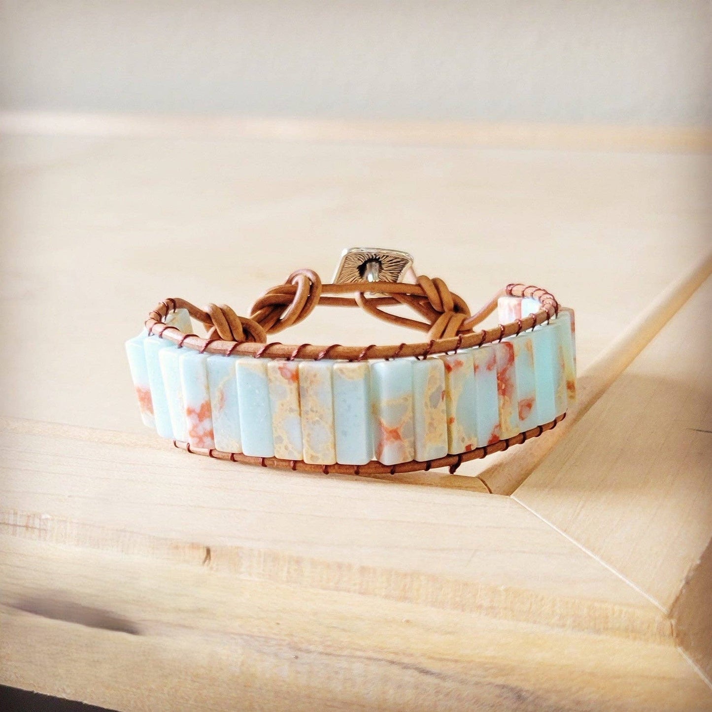 Bracelet with marbled design and brown leather strap on a wooden surface