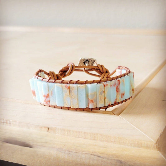 Bracelet with marbled design and brown leather strap on a wooden surface