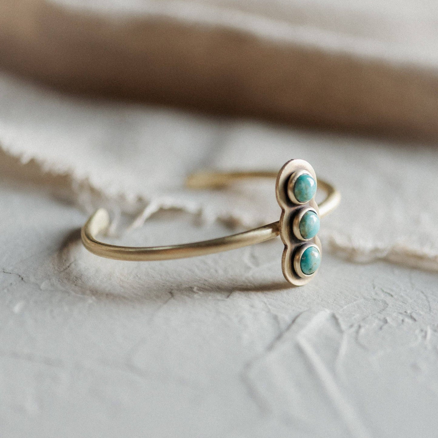 Gold ring with turquoise stones on a textured surface