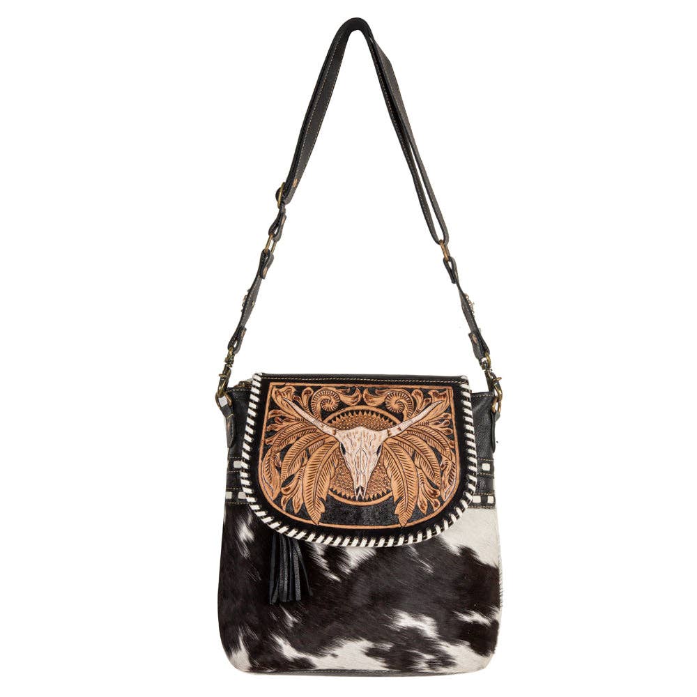 Black and white cowhide handbag with leather skull design on a white background