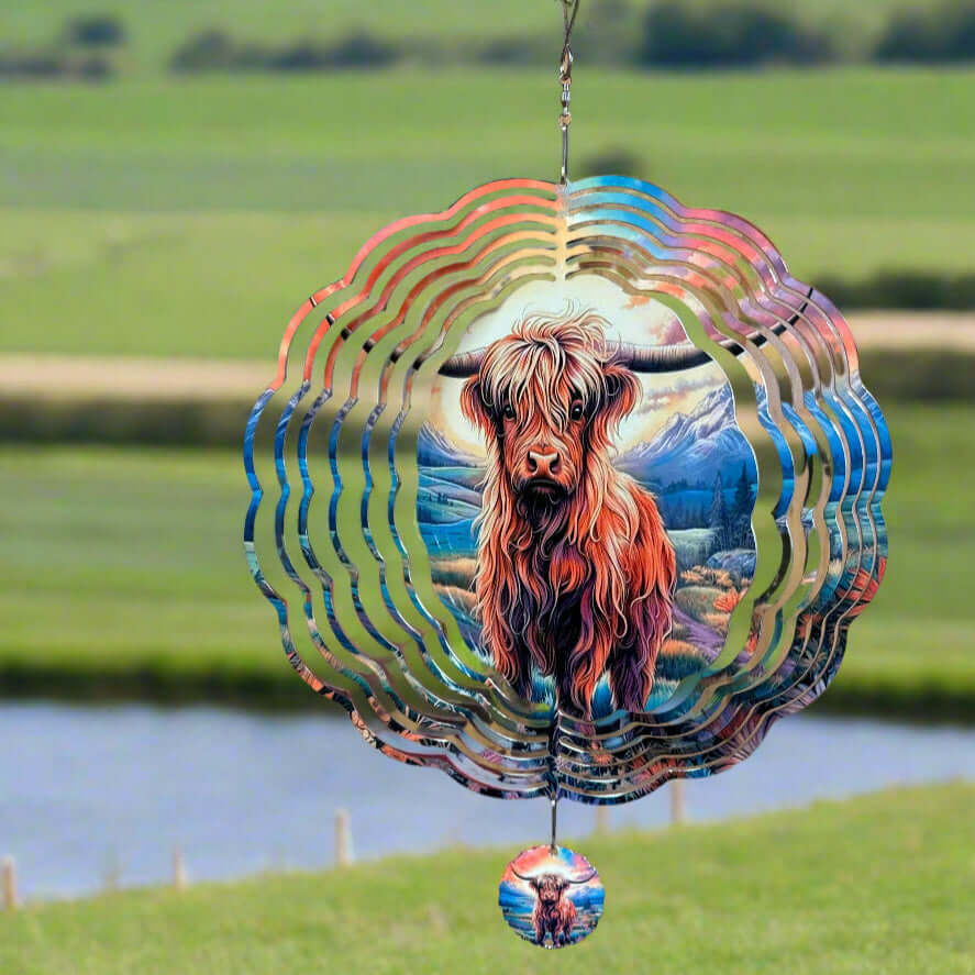Colorful wind spinner with a highland cow design in a grassy field.