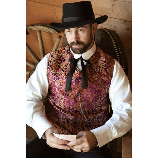 Man wearing a patterned vest and black hat in a rustic setting