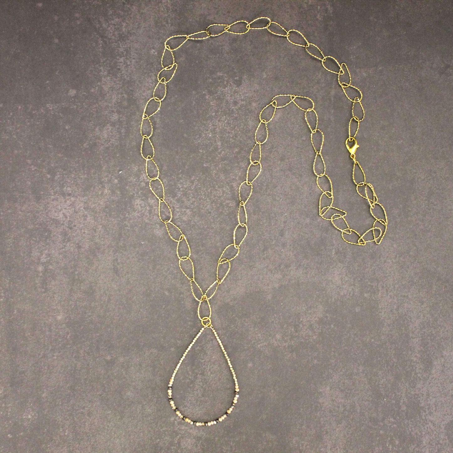 Gold chain necklace on a gray textured surface