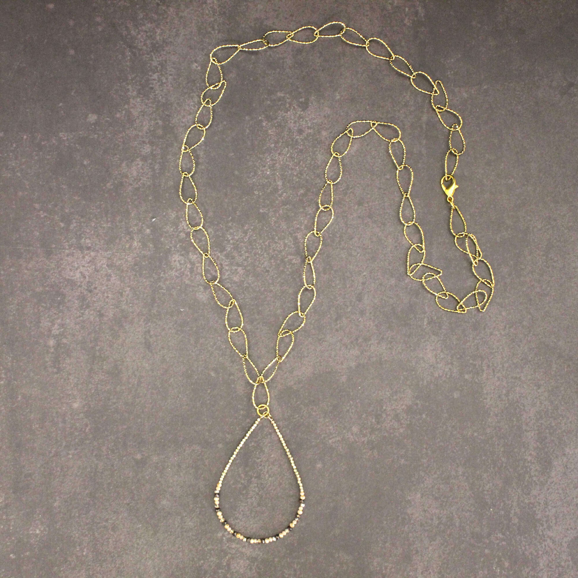 Gold chain necklace on a gray textured surface