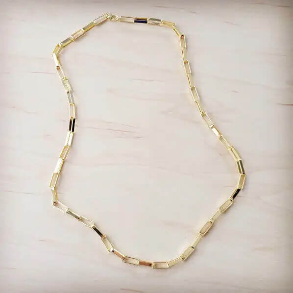 Gold necklace on a light wooden surface