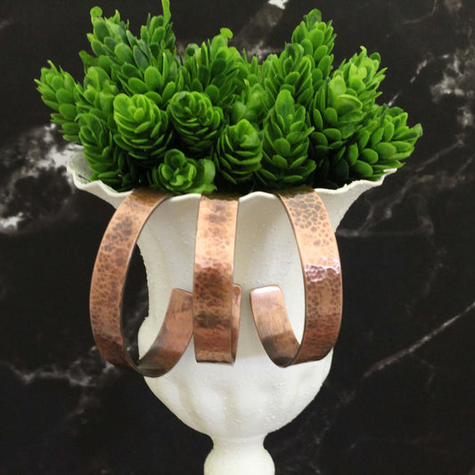 Hammered Copper Cuff J Marie Bracelet displayed in a vase with greenery, showcasing its versatile western style.