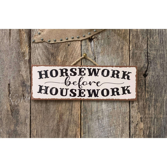 Decorative sign with 'Horsework before Housework' text on a wooden background