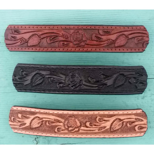 Three leather barrettes with floral embossing on a teal background