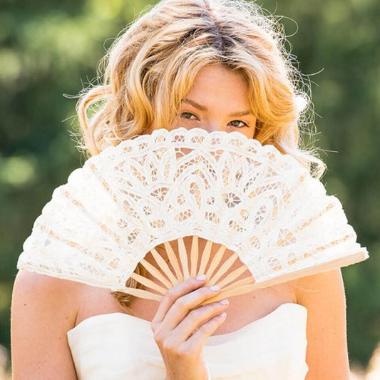 Woman holding a lace fan outdoors with a blurred green background