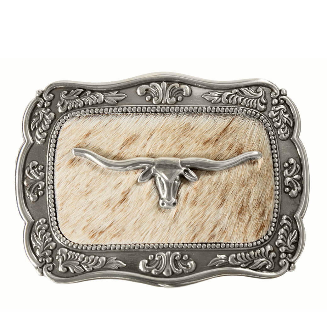 A western-style belt buckle featuring an ornate silver-toned metal frame with scrollwork, a central panel of tan and cream cowhide, and a polished silver steer skull with long horns.