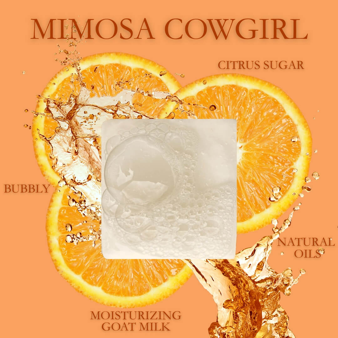 A cosmetic product shown as a square white bar centered over three orange slices on a peach background, with text reading 'MIMOSA COWGIRL,' 'CITRUS SUGAR,' 'BUBBLY,' 'NATURAL OILS,' and 'MOISTURIZING GOAT MILK.'.