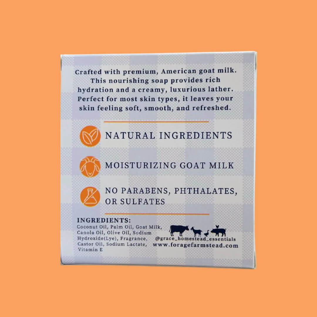 The back of a goat milk soap box, featuring product details, ingredients, and branding on a light blue-gray textured background, set against a solid orange backdrop.
