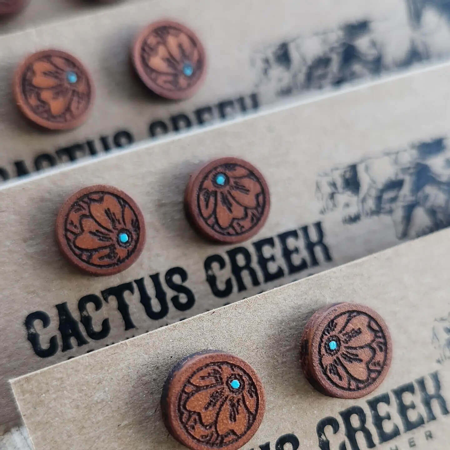 Brown leather earrings with turquoise stones on a Cactus Creek branded card.
