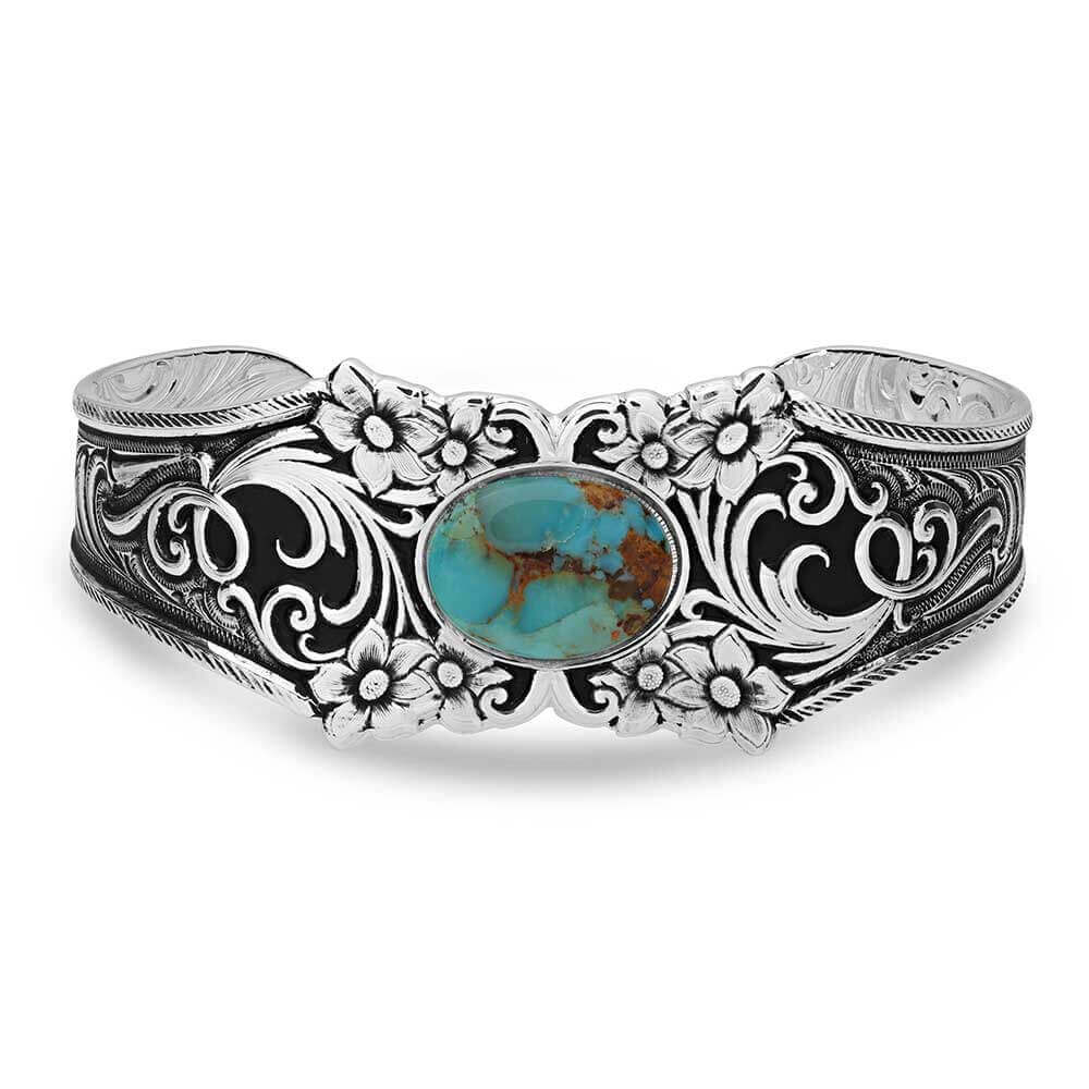 Silver bracelet with floral patterns and a turquoise stone on a white background