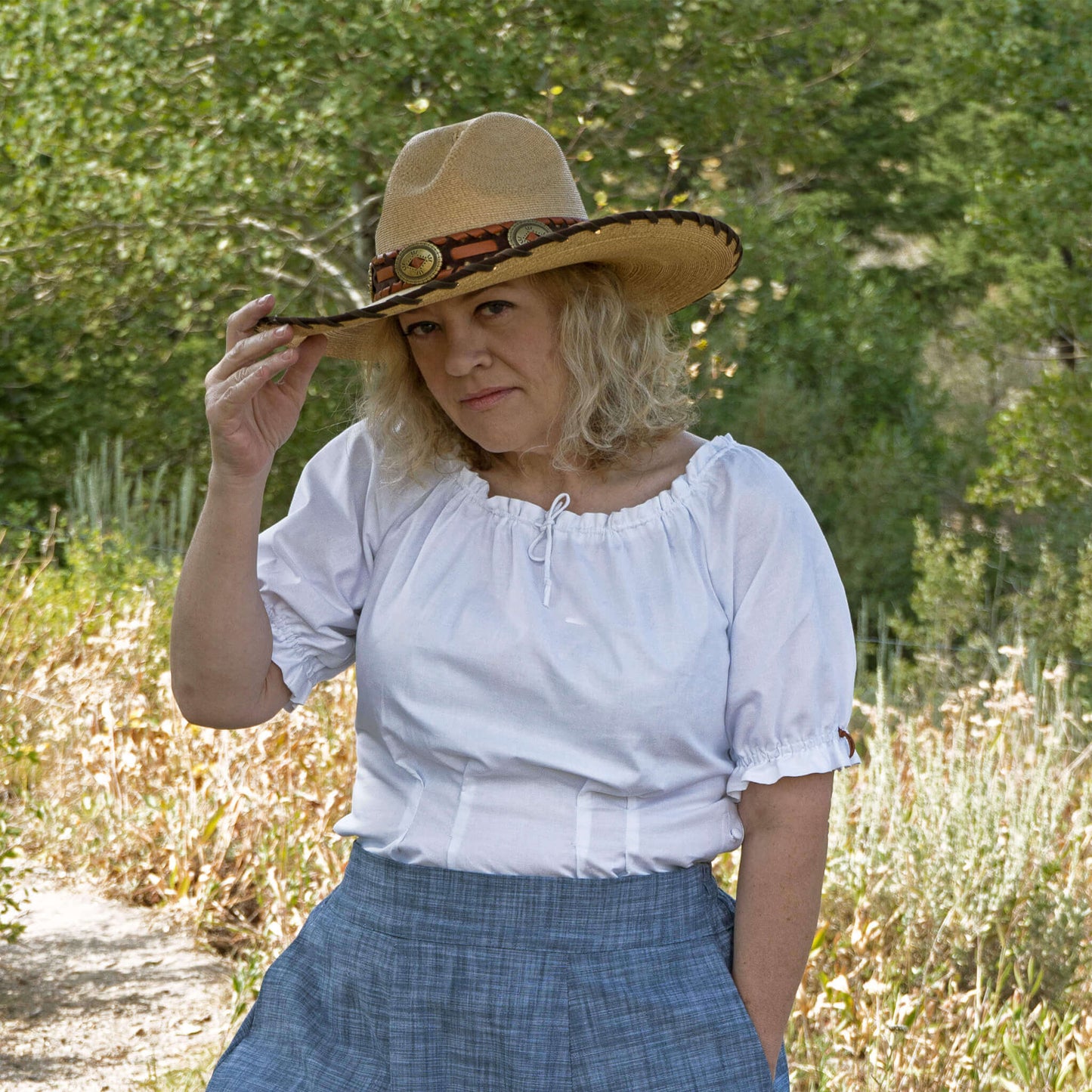 Woman wearing Olmstead Women's Western Peasant Blouse and a cowboy hat in a natural outdoor setting.