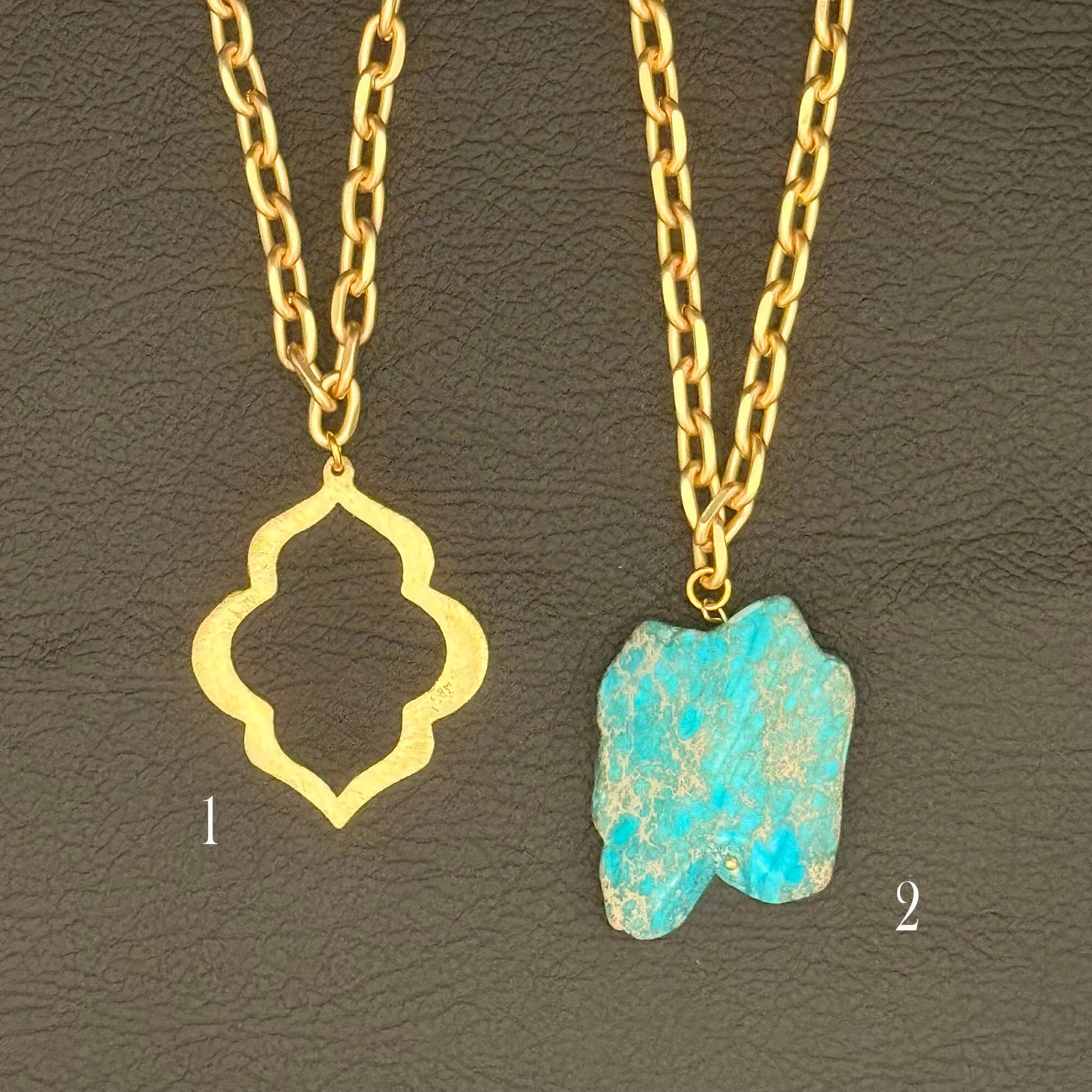 Two gold chain necklaces displayed on a dark textured background. Necklace 1 features a gold quatrefoil-shaped pendant, and necklace 2 features a turquoise-blue marbled stone pendant with gold veins.