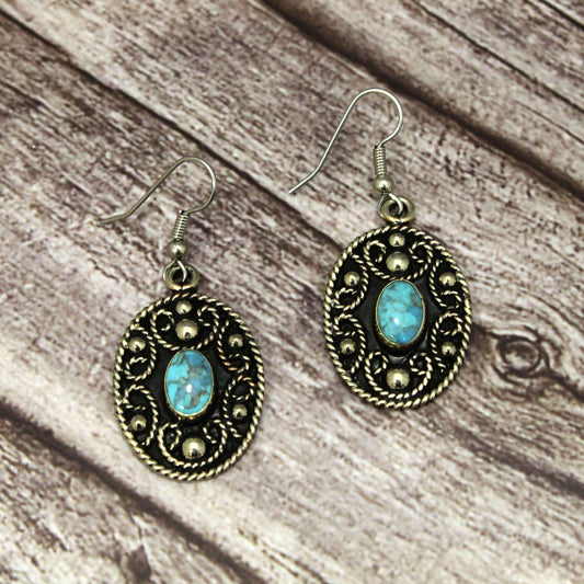 Pair of earrings with turquoise stones on a wooden surface