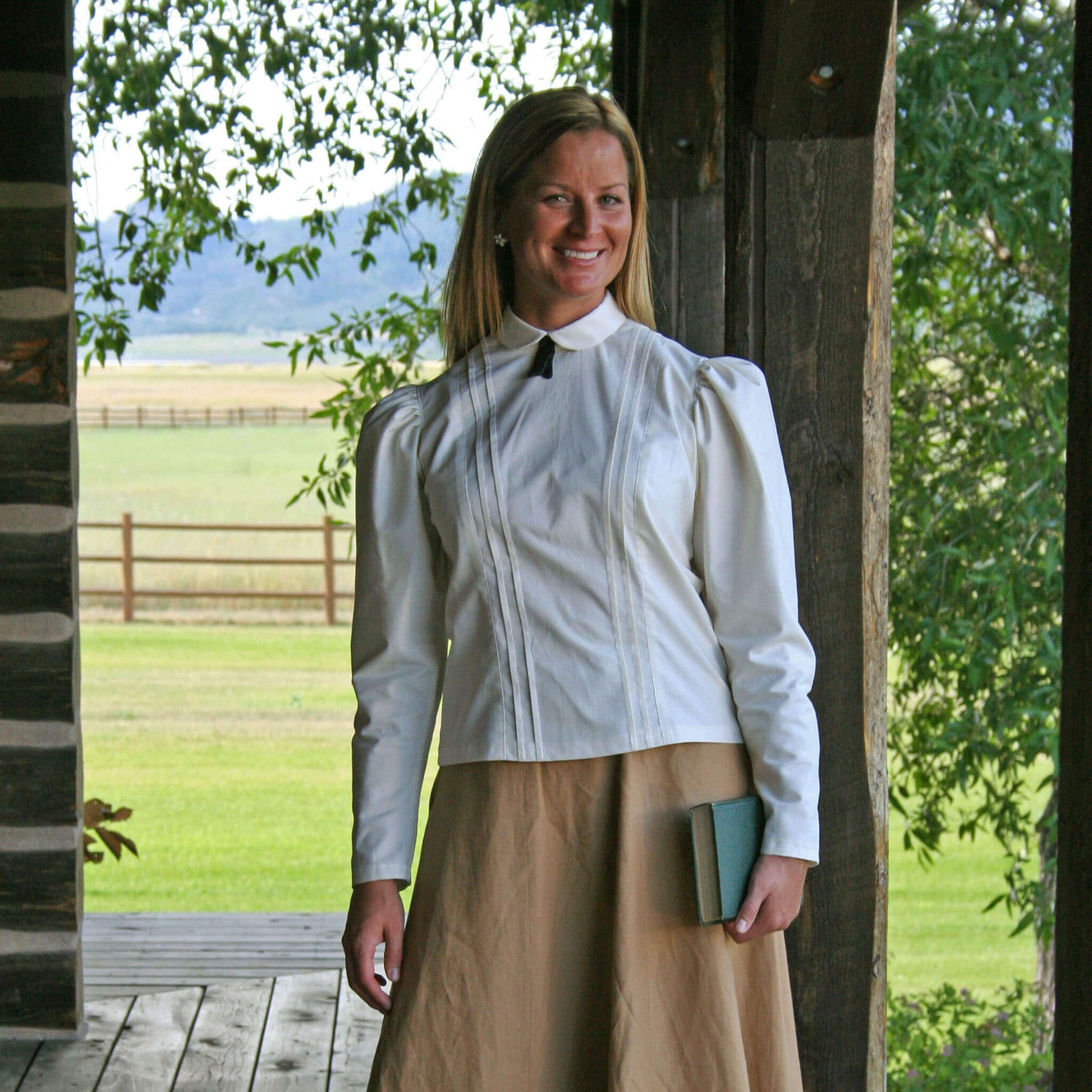 Model wearing a Schoolmarm Country Blouse with puffed sleeves and a black silk tie outdoors.