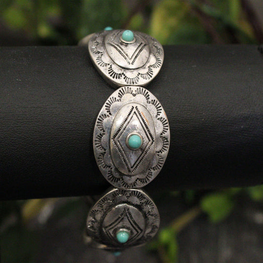 This one-size-fits-most ladies western bracelet features beautifully etched silver Conchos,&nbsp; making it a versatile piece for any occasion. The small turquoise stone adds a pop of color, perfectly complementing your existing western jewelry collection. Wear it alone for a classic look or stacked with other bracelets for a bolder statement. Elastic comfort fit. Conchos measure 1/2" wide.