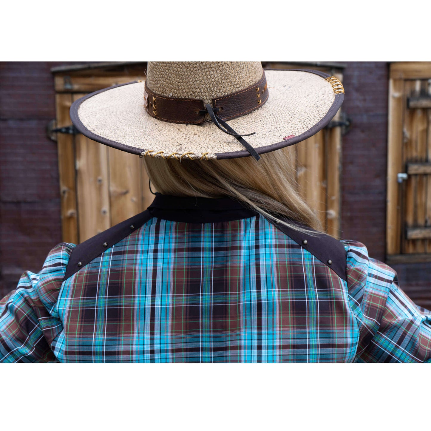 Back view of a woman wearing a Two-Step Women's Western Shirt with plaid design and a straw hat.