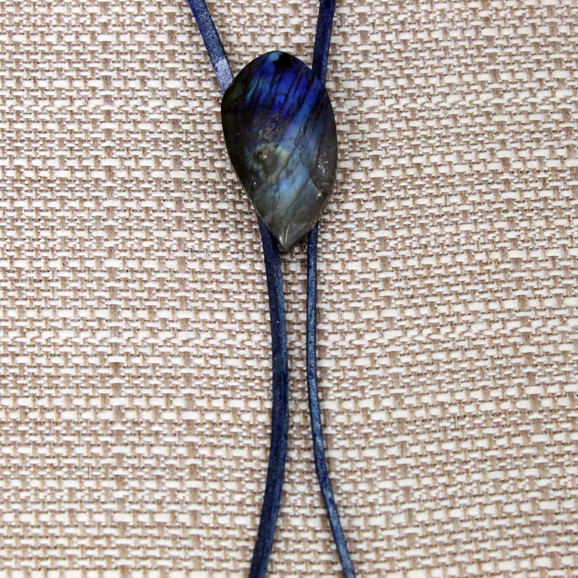 Bolo Tie with a dark blue labradorite on a beige textured background