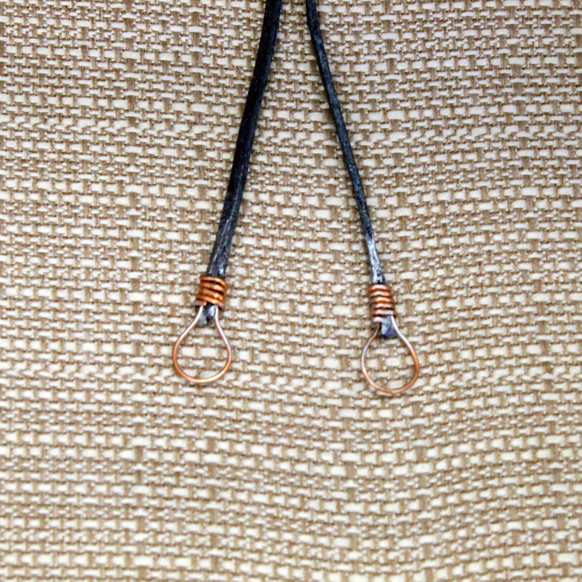 Two black lanyards with metal hooks on a textured beige background