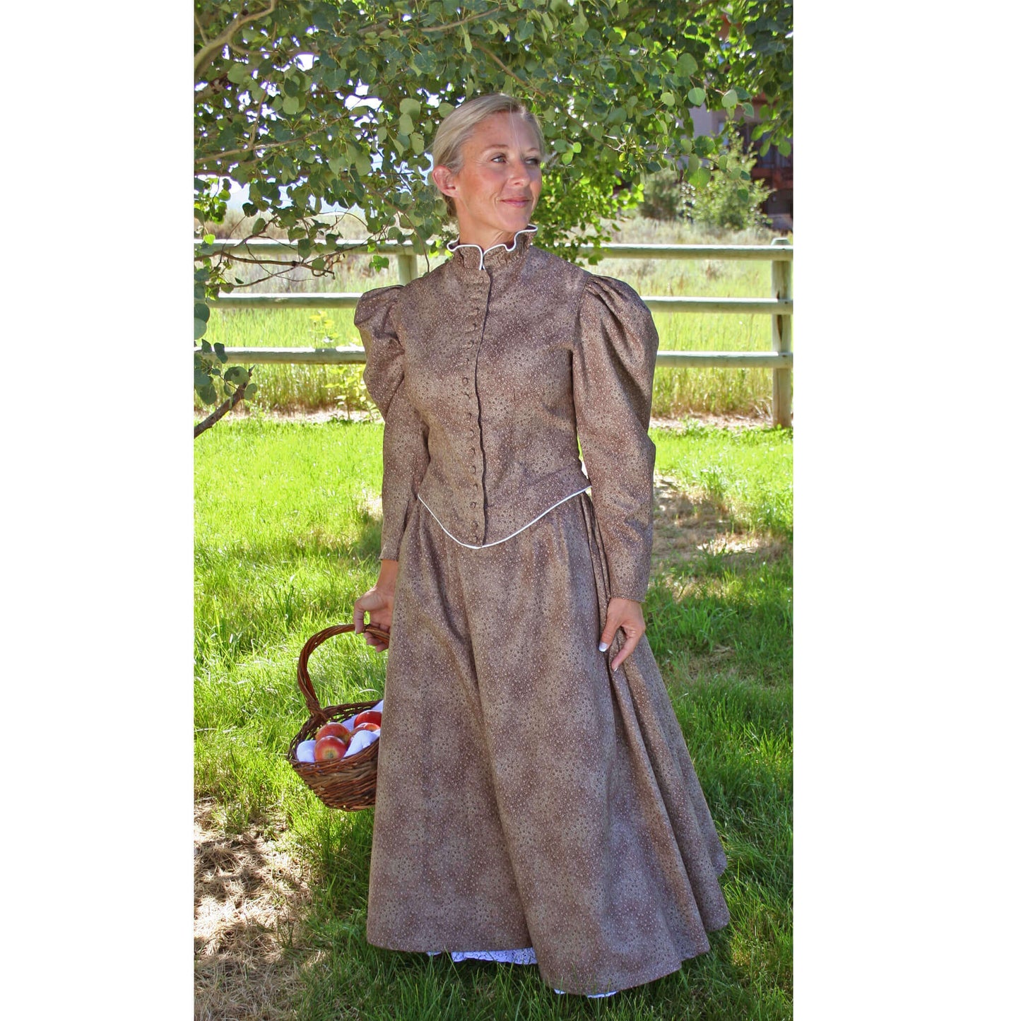 Woman in a vintage Old West walking outfit with puffed sleeves, standing in a grassy outdoor setting, holding a basket.