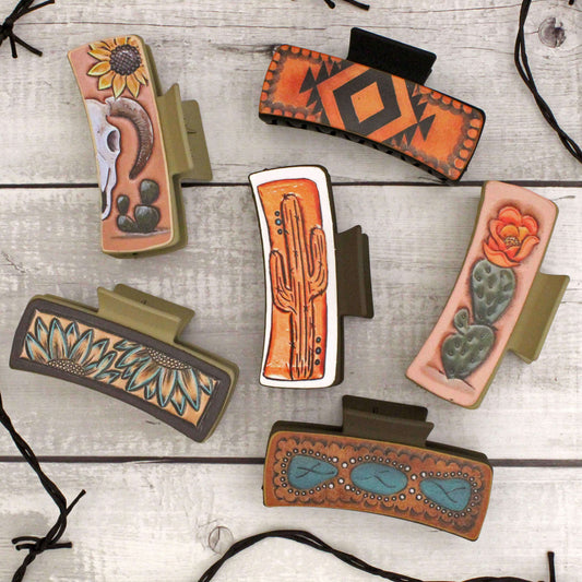 Collection of decorative hair clips with tribal and nature-themed designs on a wooden surface.