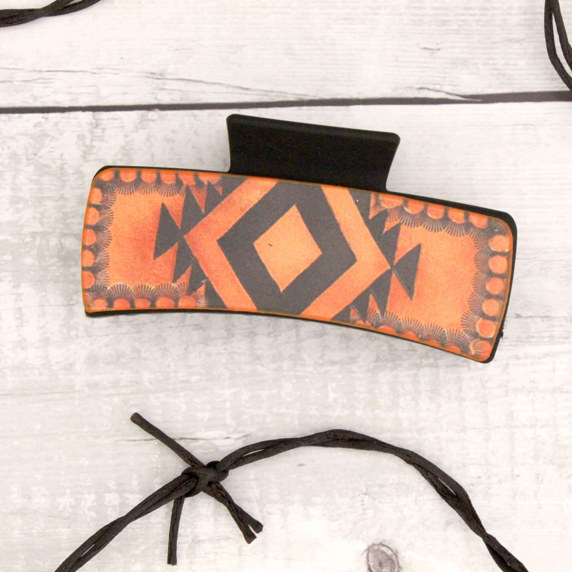 Orange and black patterned hair clip on a light gray background