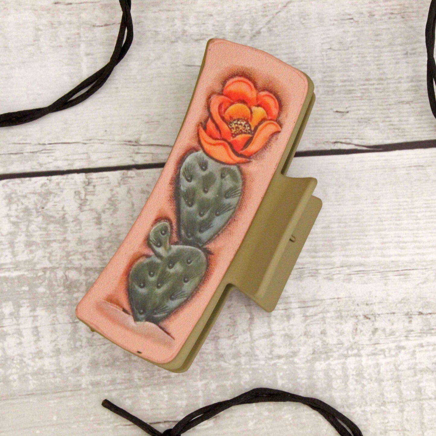 Western hair claw with a cactus and flower design on a wooden surface