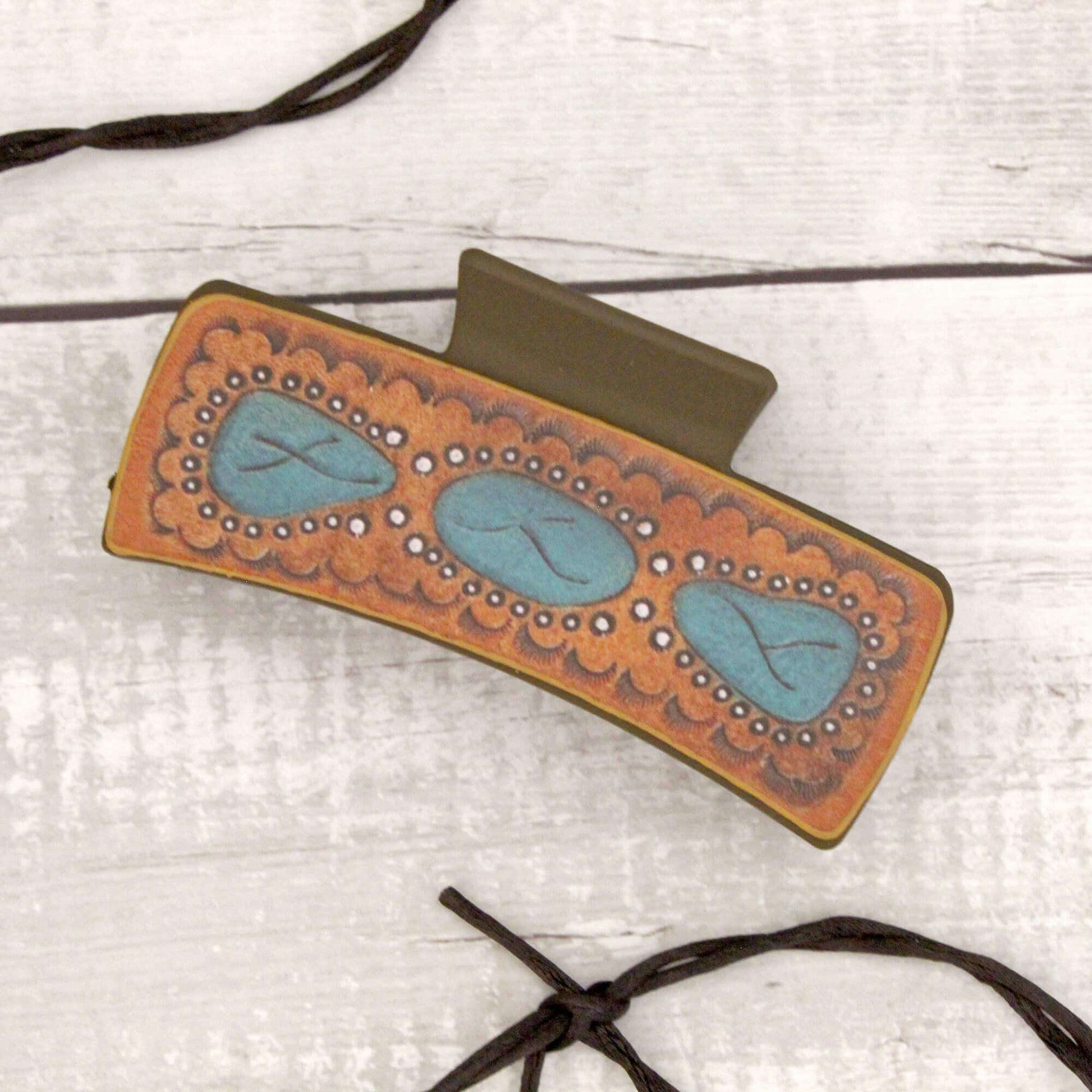 Decorative hair clip with turquoise stones on a light wooden surface