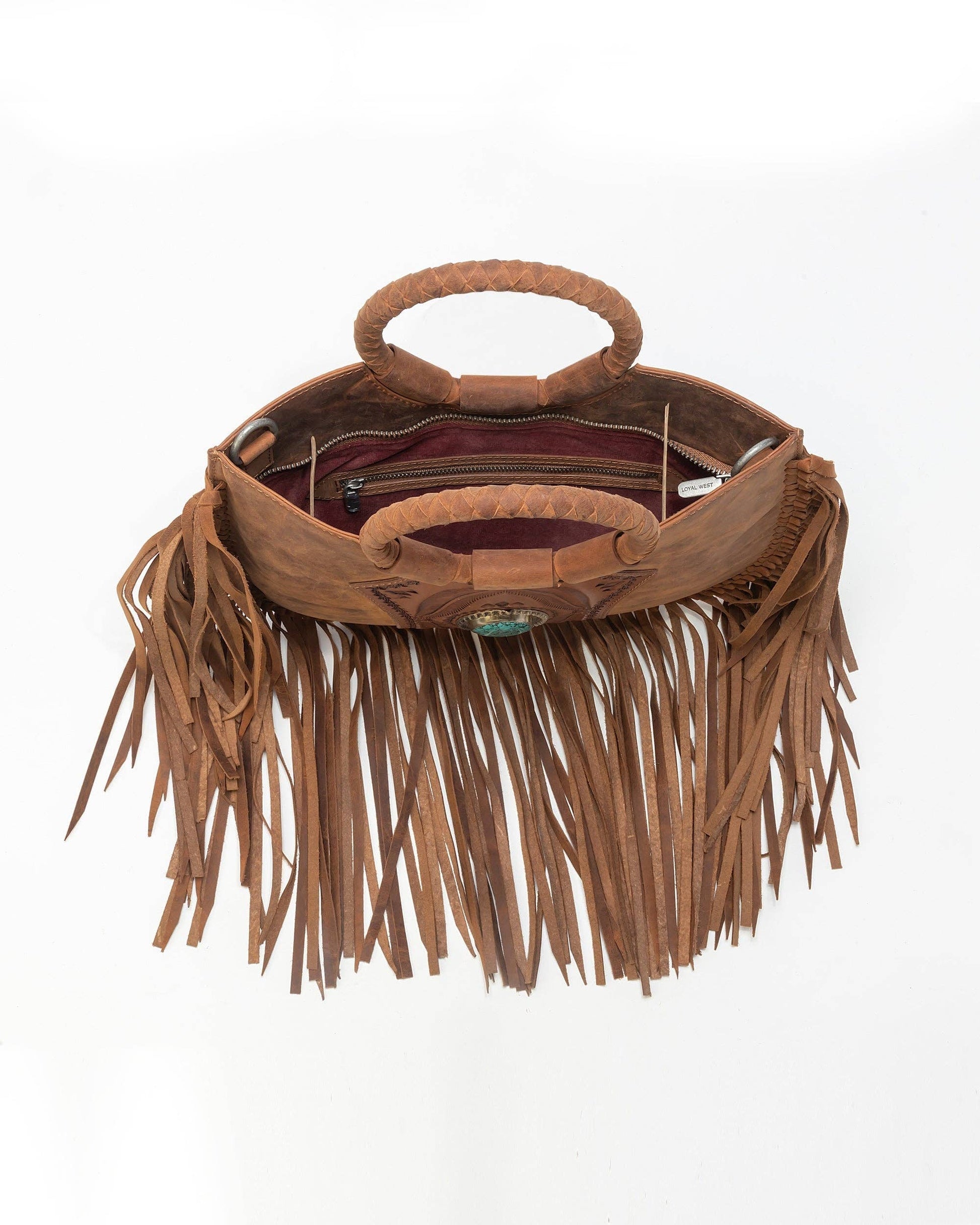 Brown leather handbag with fringe details on a white background