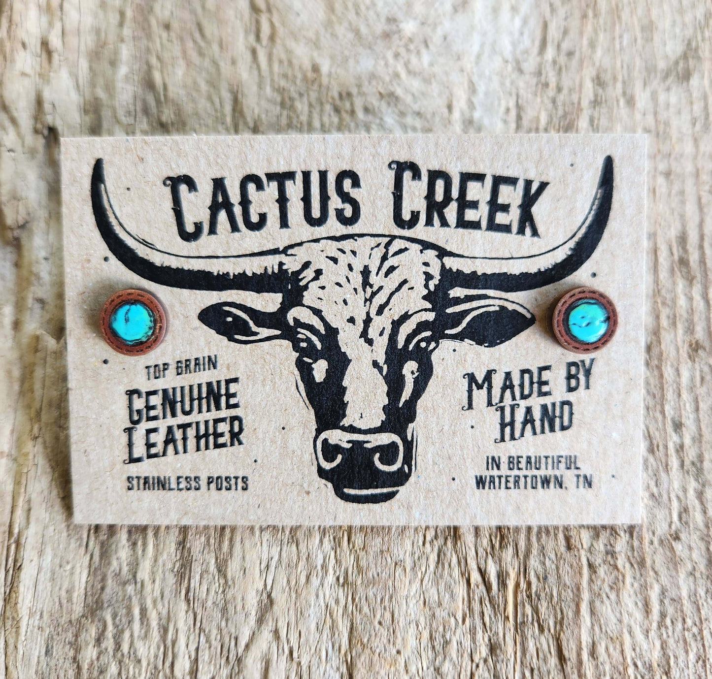 Cactus Creek leather earring card with bull illustration on a wooden surface