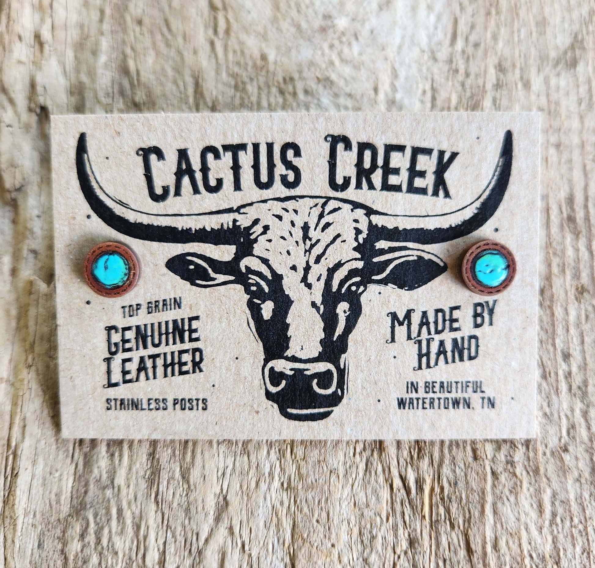 Cactus Creek leather earring card with bull illustration on a wooden surface