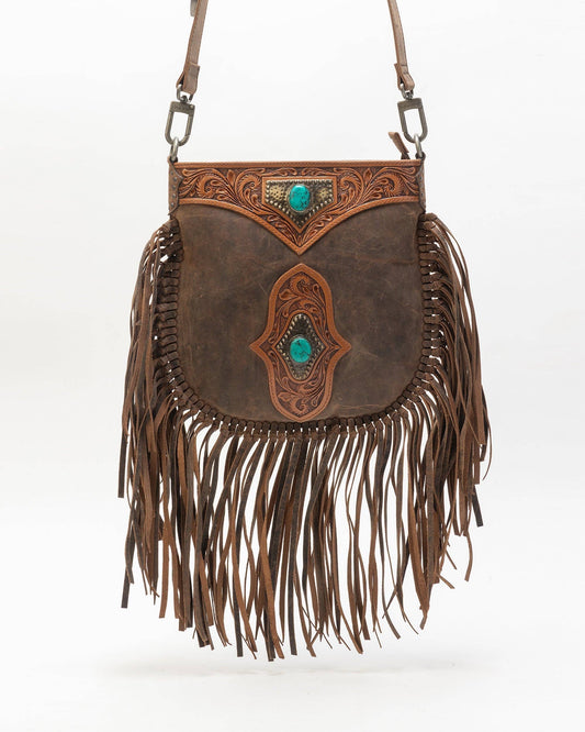 Brown leather handbag with fringe and intricate designs on a white background