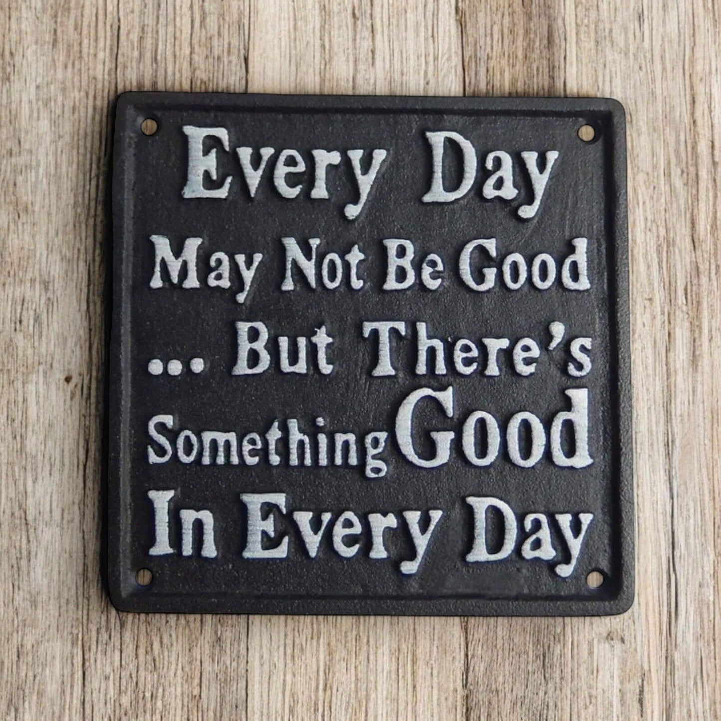 Decorative metal sign with motivational quote on a wooden background