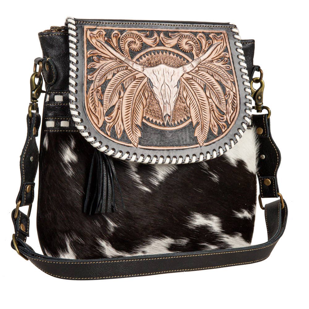 Handbag with cowhide pattern and decorative leather flap on a white background