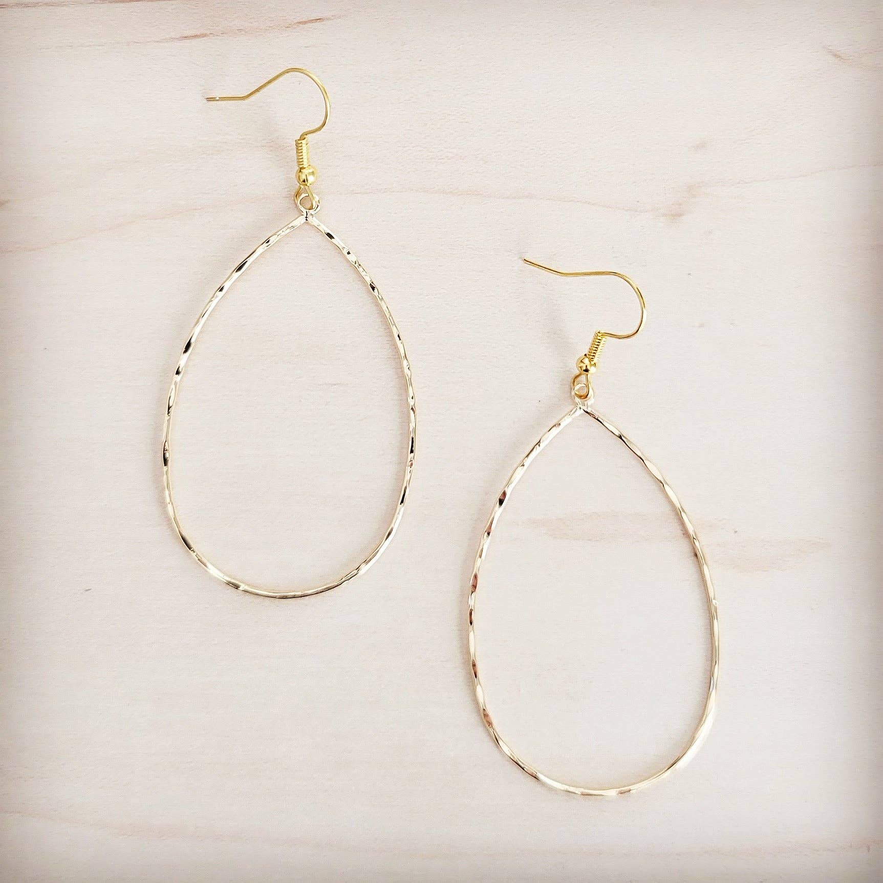 Gold hoop earrings on a light beige background