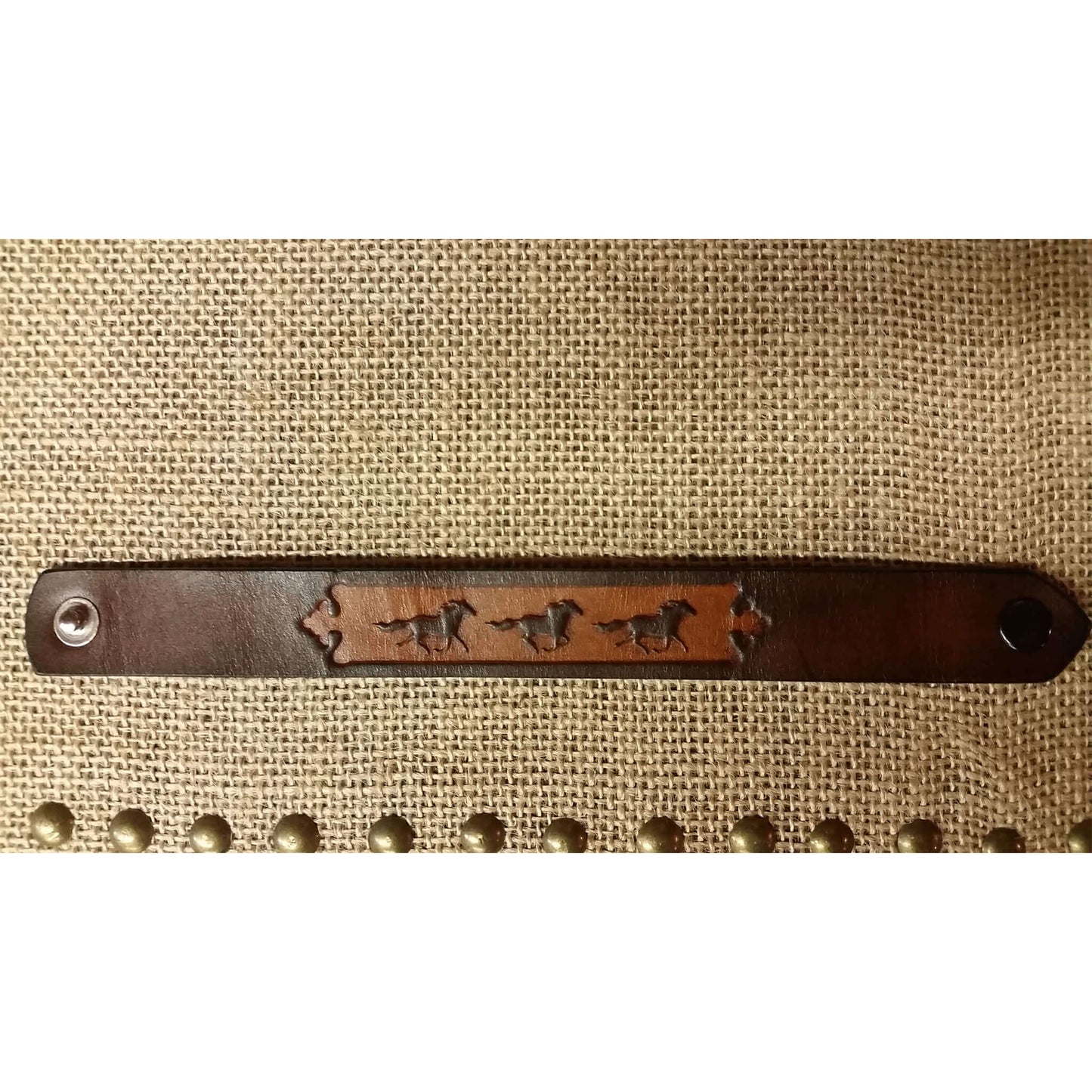 Show your love for horses! This bracelet with running horses embossed on a leather band should do the trick. Measures 7/8" wide and approximately 7" when closed.