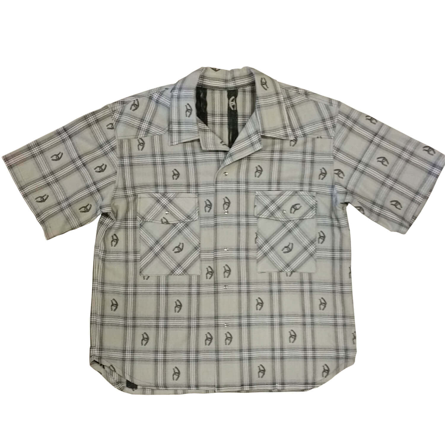 Stay stylish and cool in this short sleeve cotton shirt. Woven designs of horseshoes scatter the plaid pattern adding western flair. Two front pockets and pearl snap closures. Great for parties or concerts or any summer event that you need to look your best. Made in USA 